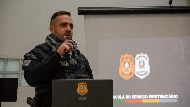 Na foto, um homem com roupa preta, segura um microfone